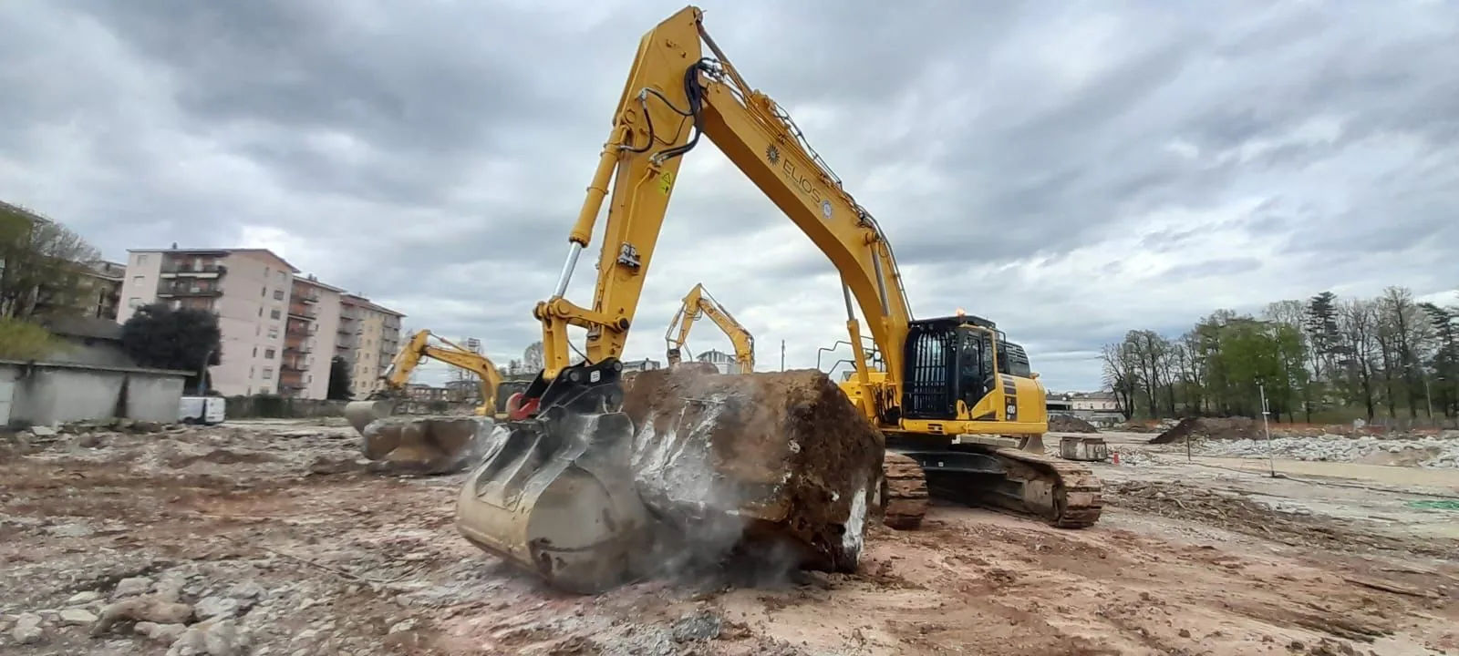 Escavatore ELIOS Ambiente che solleva un grosso blocco di fondazione demolita nell’area Ex ABB a Lodi