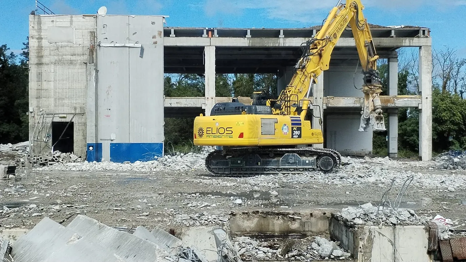 Escavatore ELIOS Ambiente con cesoia davanti alla struttura in cemento di un edificio dell’ex stabilimento Gefco-Citroën a Pregnana Milanese, tra le macerie della demolizione